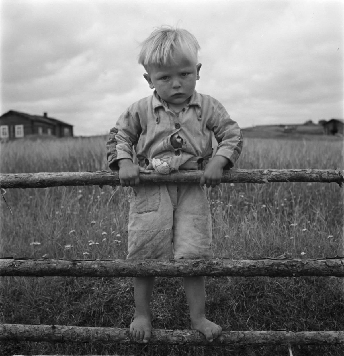 Linja-autoa katsomaan tullut poika seisoo aidalla Suomussalmella 1939. Kuva: Uuno Peltoniemi / Museoviraston Kuvakokoelmat