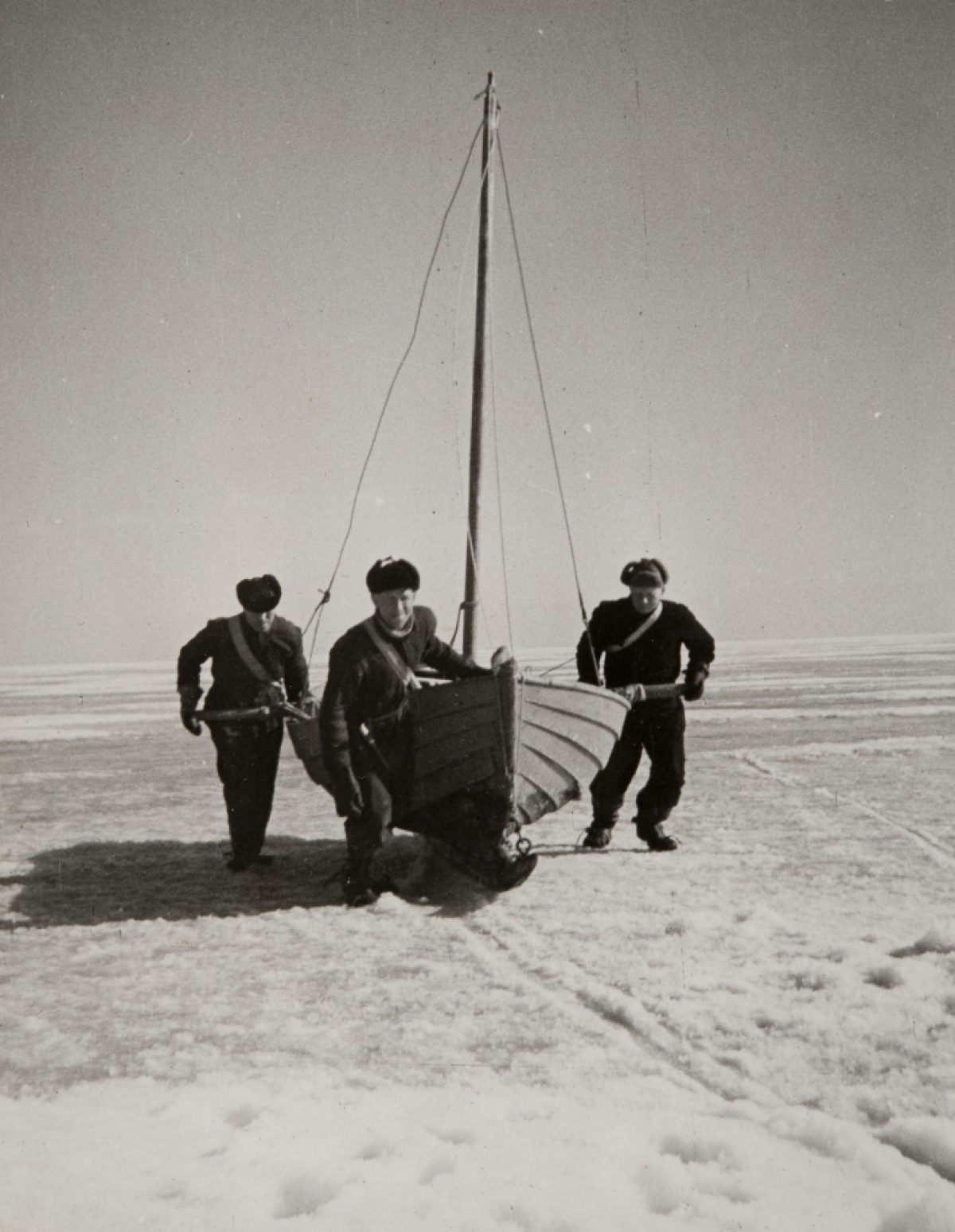 Seal hunters pulling their boat across ice in the Gulf of Finland, off the shores of Haapasaari.​ Photo: Jorma Jussilainen / Picture Collections of the Finnish Heritage Agency
