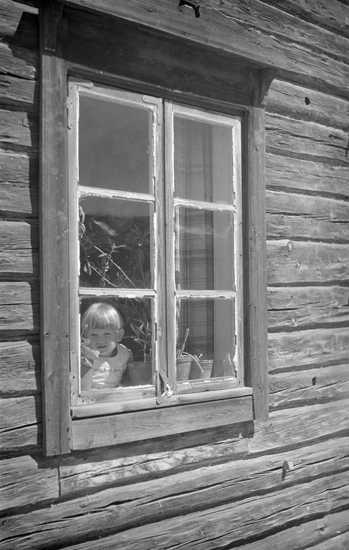 Ett barn i ett fönster i Hartola. Foto: Matti Poutvaara / Museiverkets Bildsamlingar